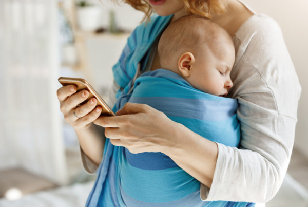 mom looking at phone while holding baby