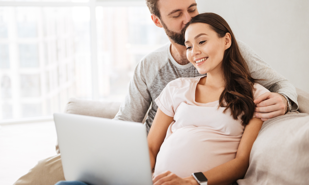 Pregnant couple researching childcare online