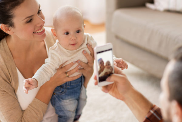 Dad taking photo of mom and baby with smartphone