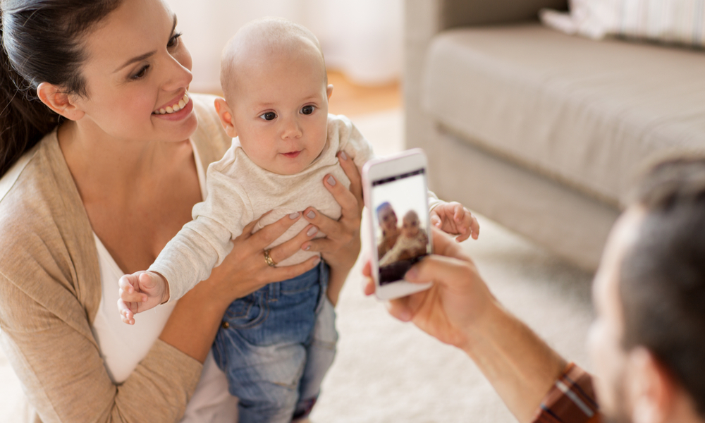 Dad taking photo of mom and baby with smartphone