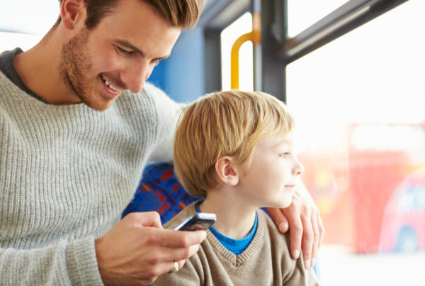 Dad reading online reviews while riding bus with son