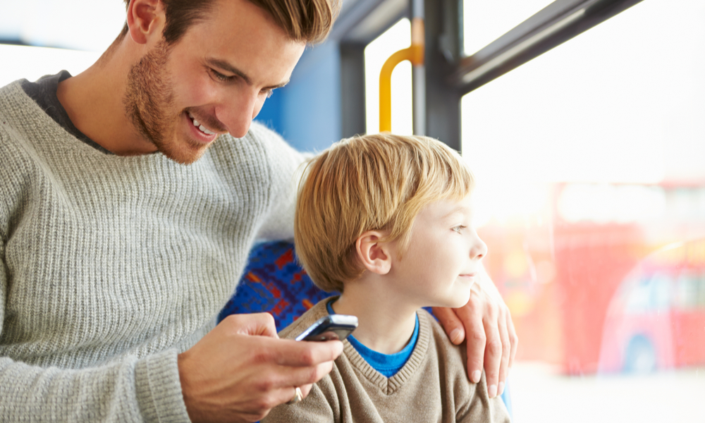 Dad reading online reviews while riding bus with son