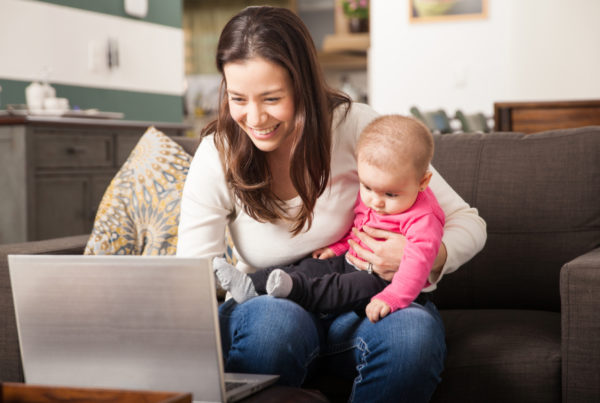 Mom on laptop while holding infant