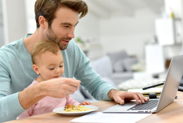 Dad on laptop with baby in lap