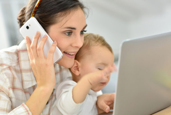 Mother on phone and laptop with baby