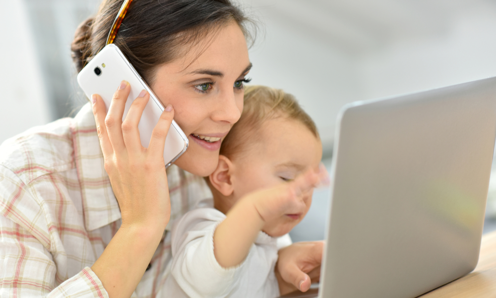 Mother on phone and laptop with baby